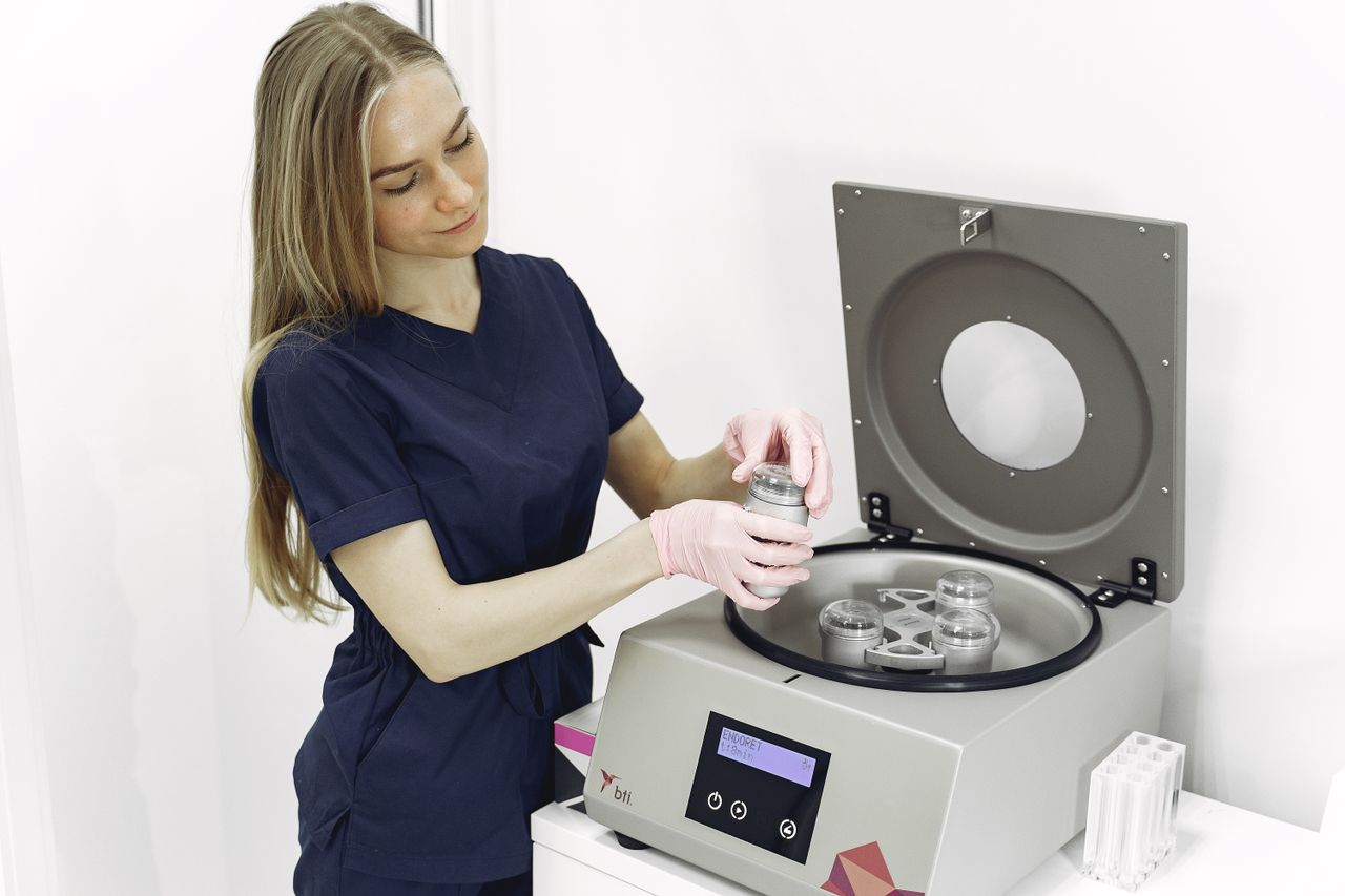 A nurse in a lab setting uses medical equipment to prepare samples.